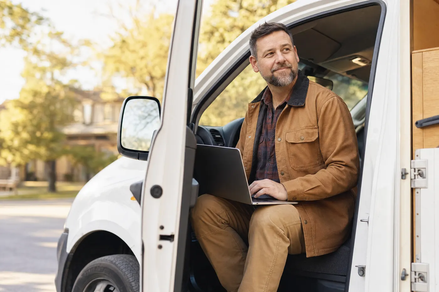 Business owner working on a laptop in the door of his work truck